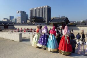 Visitors in hanbok at Gyeongbokgung watching the royal guard outside the palace gate