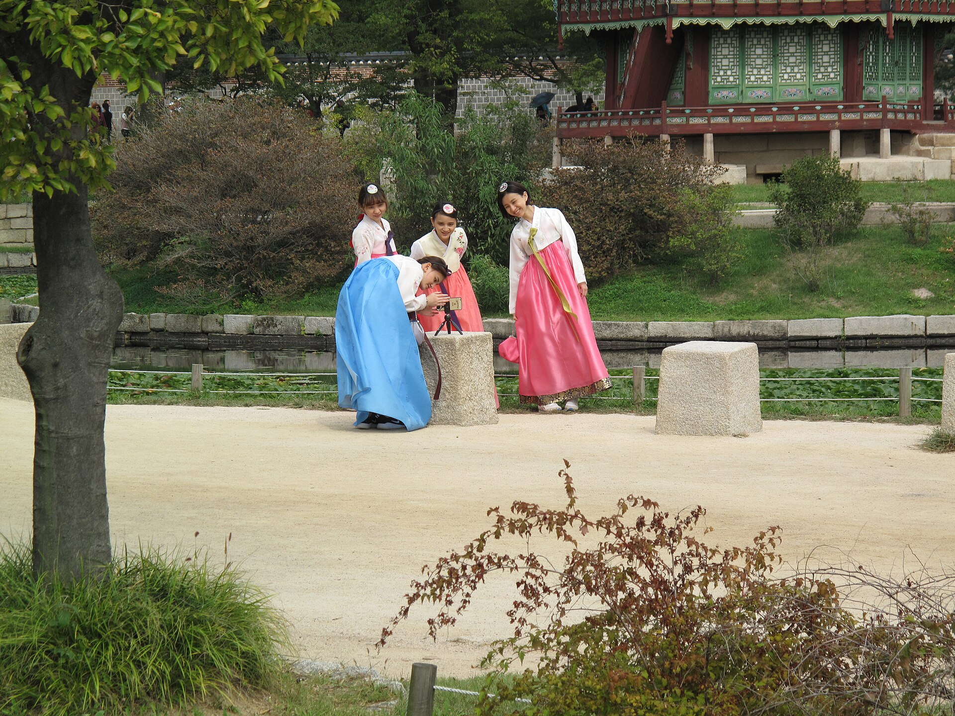 Friends in hanbok taking a photo near Hyangwonjeong pond inside Gyeongbokgung