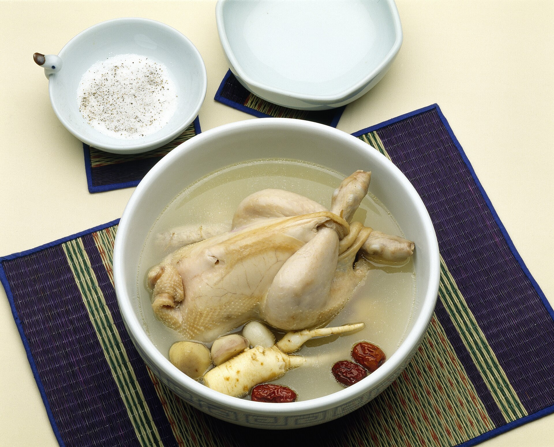 Samgyetang with a whole young chicken, ginseng, jujubes and chestnuts, served with a dish of salt and pepper